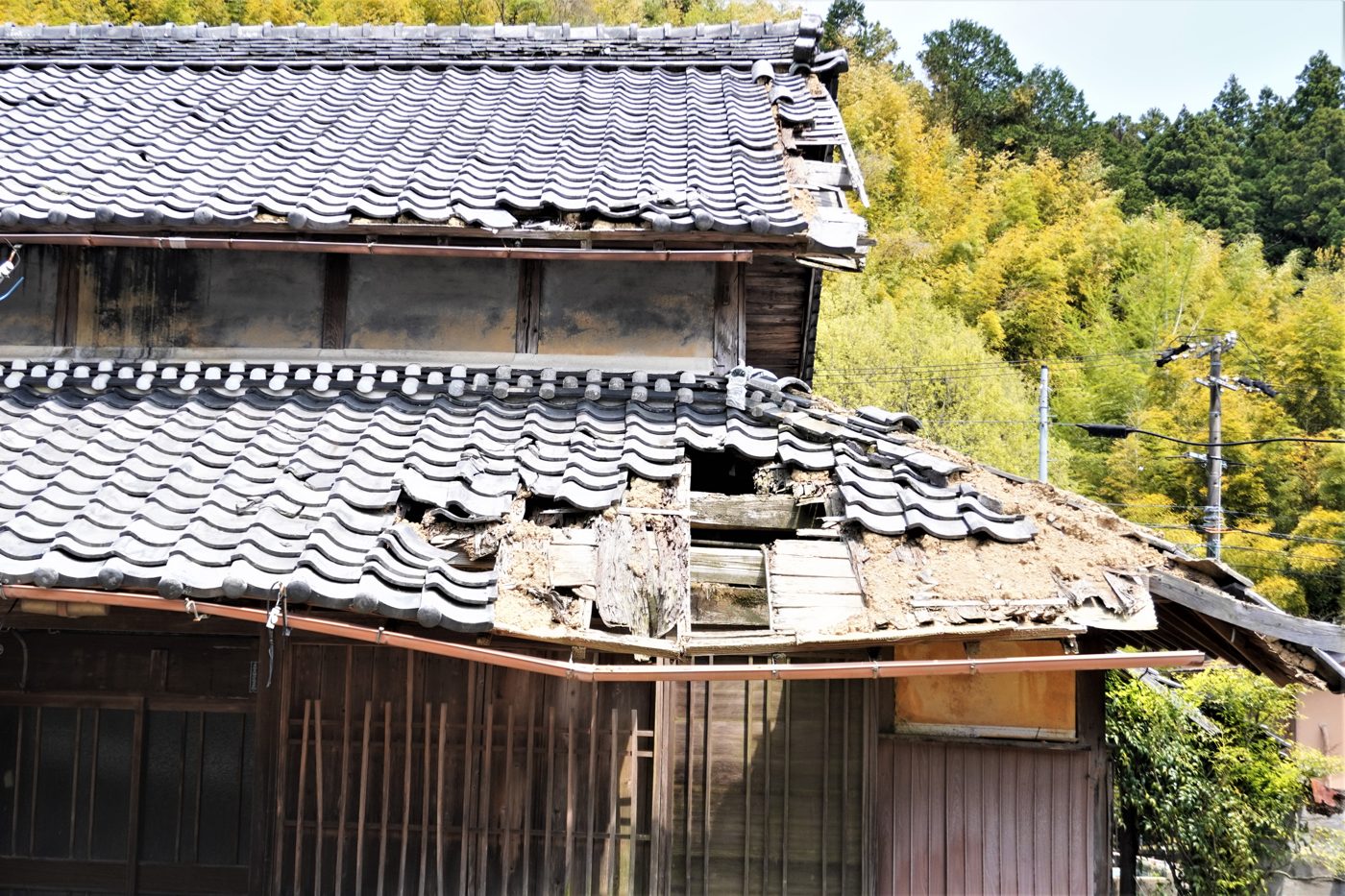瓦屋根が崩れかけた古い木造住宅