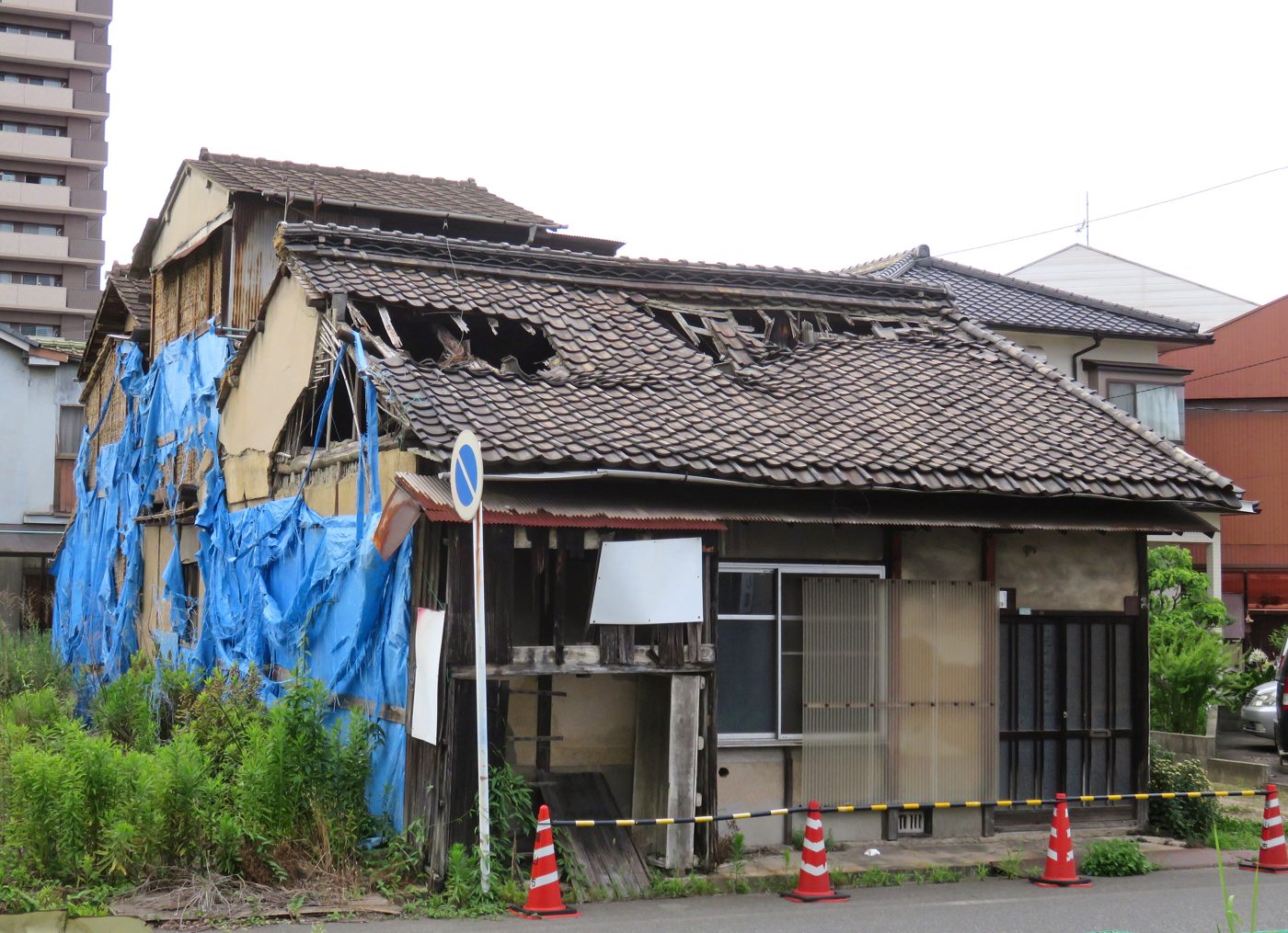 ブルーシートで覆われた傷みの激しい平屋の空き家