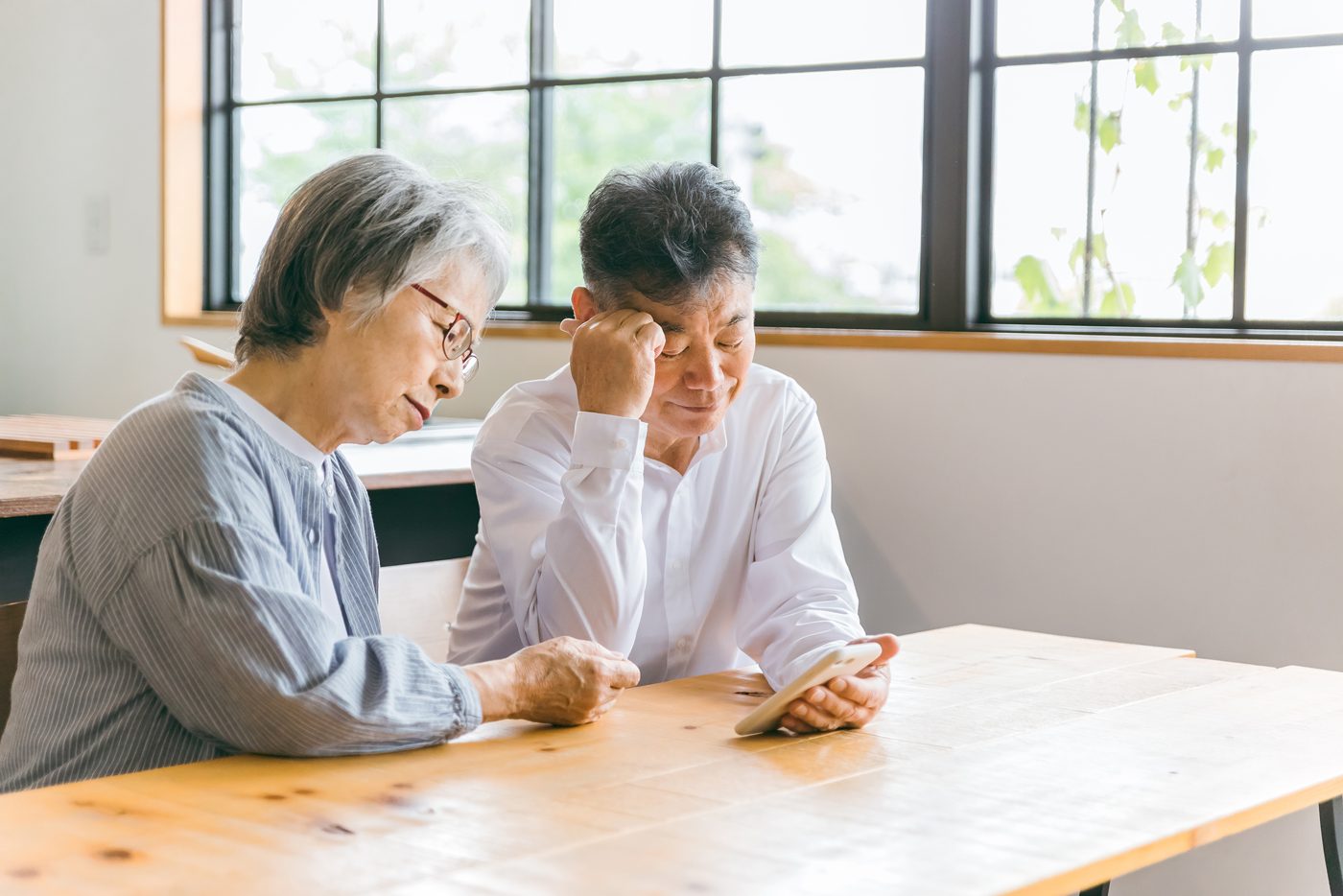 スマートフォンを見ながら悩む高齢のご夫婦
